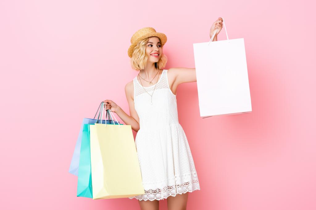 młoda kobieta w białej sukience trzyma torby na zakupy na różowy  - Zdjęcie, obraz