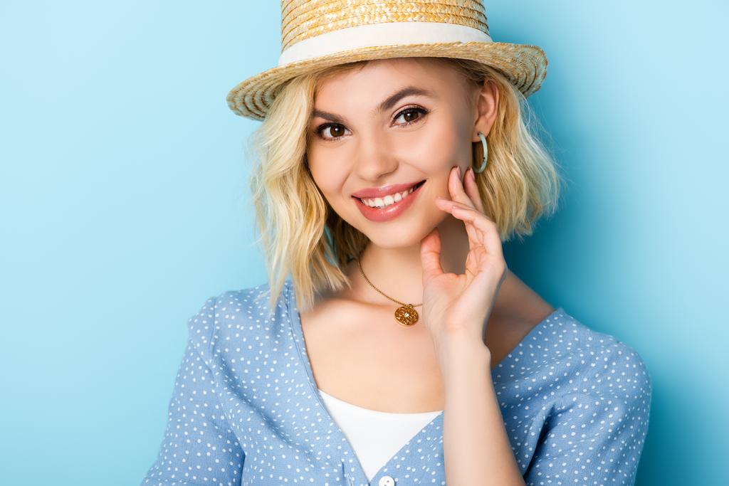 young woman in straw hat looking at camera on blue  - Photo, Image