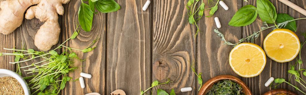 panorámás lövés tabletták és zöld gyógynövények fa felületen, természetgyógyászat koncepció - Fotó, kép