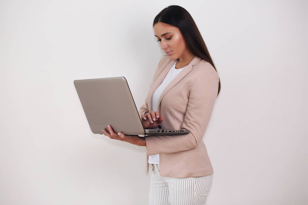 Portret van opgewonden jonge brunette meisje met laptop computer, geïsoleerde achtergrond - Foto, afbeelding
