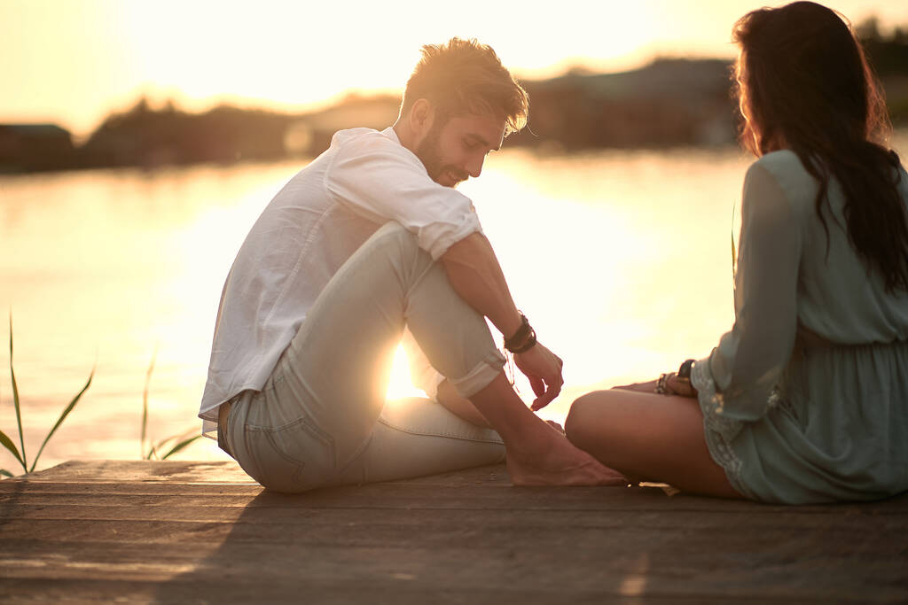 Jeune couple amoureux ayant des moments tendres romantiques sur la rivière au coucher du soleil. - Photo, image