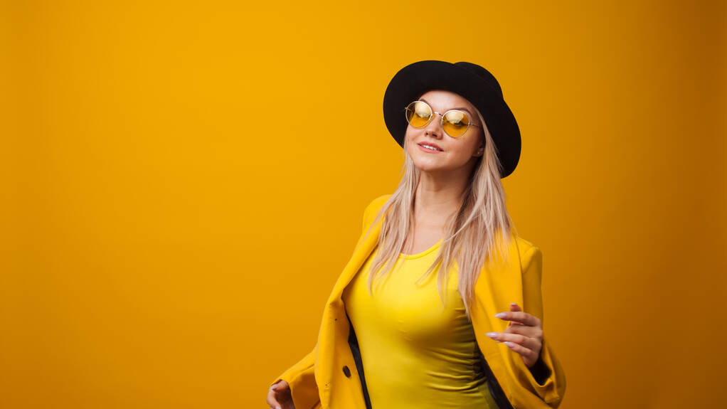 Veselá trendy mladá žena v zářivé šaty na žlutém pozadí, kopírovat prostor. Cool blondýnka - Fotografie, Obrázek