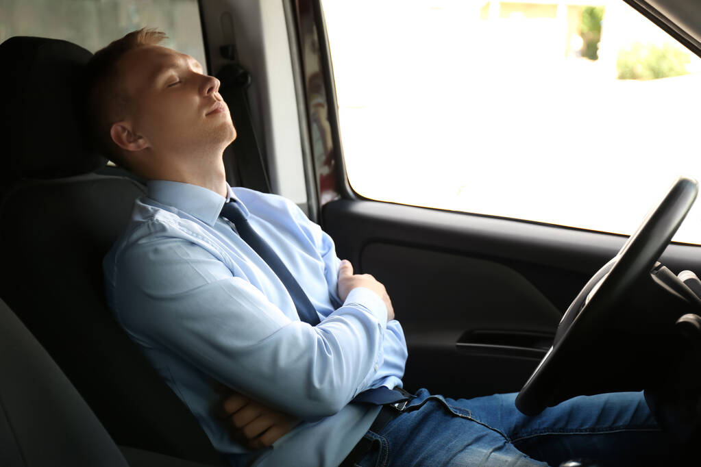Zmęczony młodzieniec śpiący w swoim nowoczesnym samochodzie - Zdjęcie, obraz