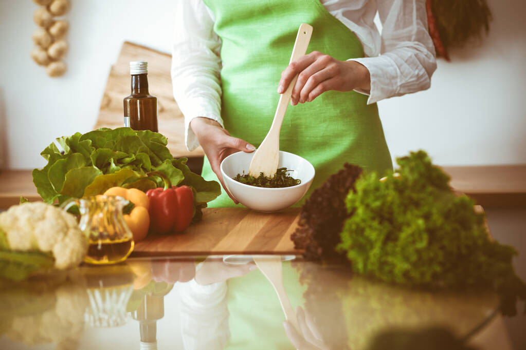 Des mains humaines inconnues cuisinent dans la cuisine. La femme est occupée avec la salade de légumes. Repas santé et concept alimentaire végétarien - Photo, image