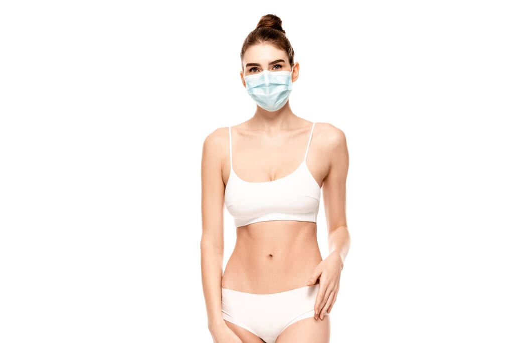 young woman in medical mask, panties and top standing isolated on white - Photo, Image