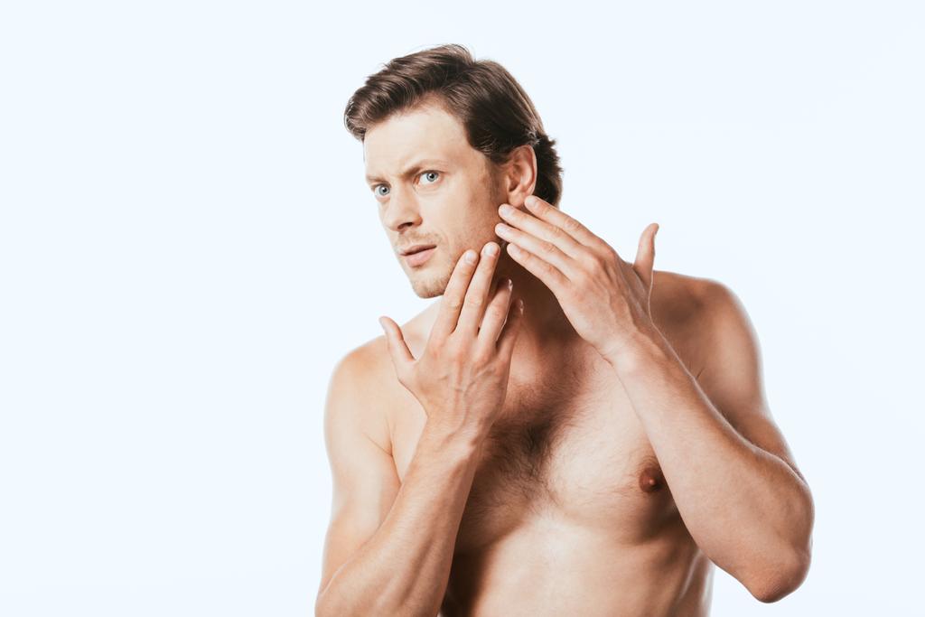 Besorgter muskulöser Mann berührt Haut auf Wange isoliert auf weißem Grund - Foto, Bild