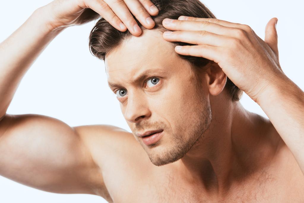 Hombre preocupado tocando el cabello y mirando hacia otro lado aislado en blanco - Foto, imagen
