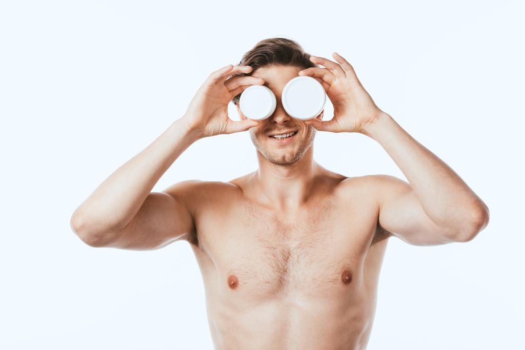 Без сорочки чоловік тримає банки косметичних кремів ізольовані на білому
 - Фото, зображення
