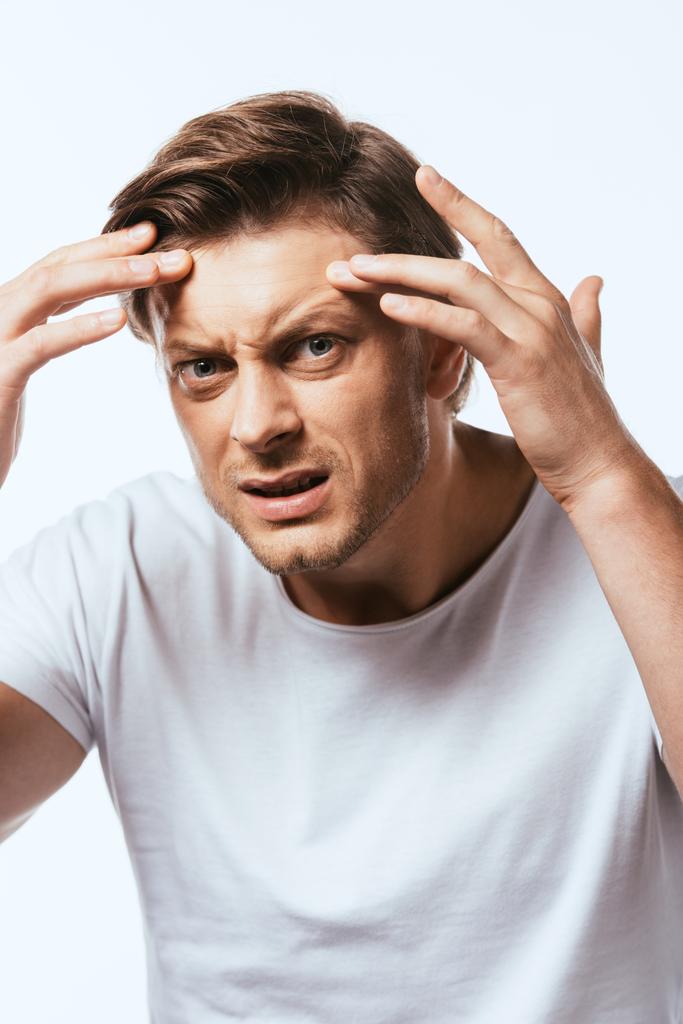 Worried man touching skin on forehead and looking at camera isolated on white - Photo, Image