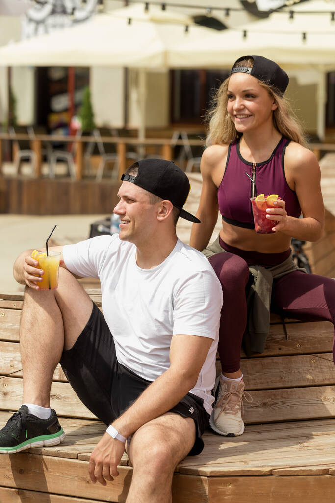 Couple sportif assis dans un café dégustant des boissons fraîches après un entraînement intensif. - Photo, image
