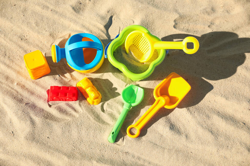 Brinquedos de plástico criança diferente na praia de areia, flat lay
 - Foto, Imagem