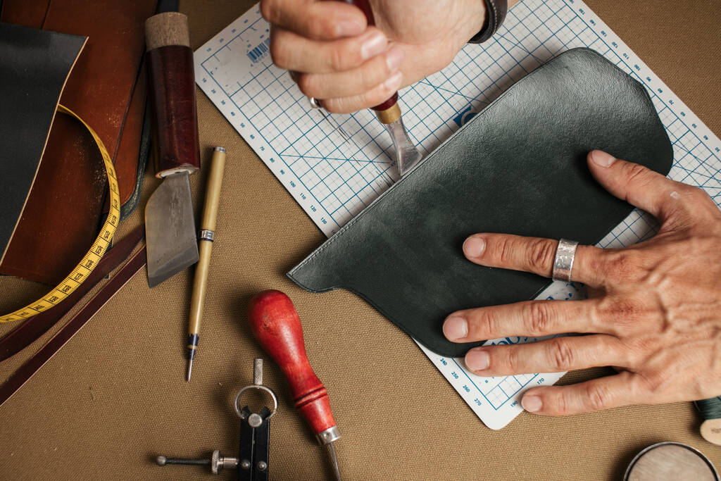 Proceso de trabajo de producción de billetera de cuero hecha a mano en el taller de cuero. - Foto, Imagen