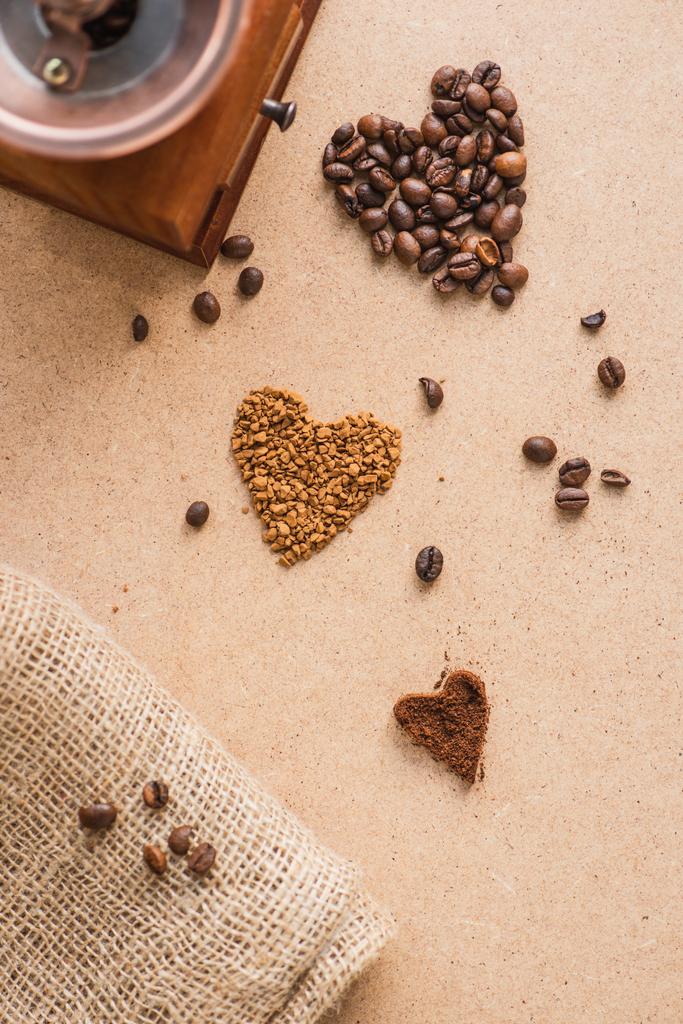 vista superior do moedor de café vintage perto de corações e serapilheira na superfície bege
 - Foto, Imagem