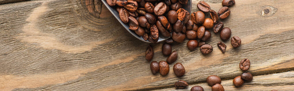 top view of metal scoop with coffee beans on wooden surface, panoramic shot - Photo, Image