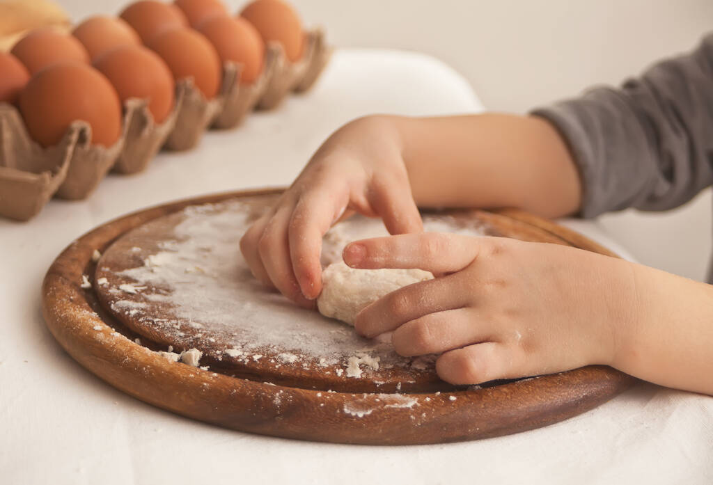 Klein kind in de keuken thuis het maken van deeg voor pizza of een ander voedsel - Foto, afbeelding