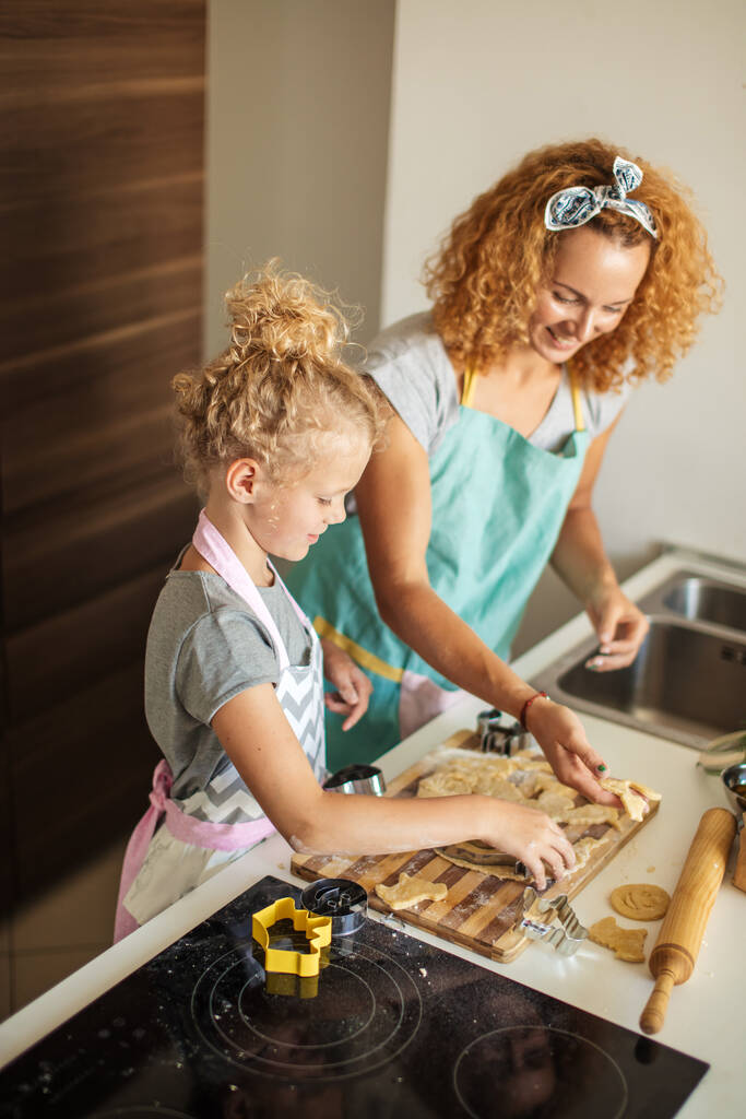 Παιδί και γυναίκες κόβουν φόρμα για μπισκότο στη ζύμη. Ευτυχισμένη οικογένεια και παιδική ηλικία. - Φωτογραφία, εικόνα