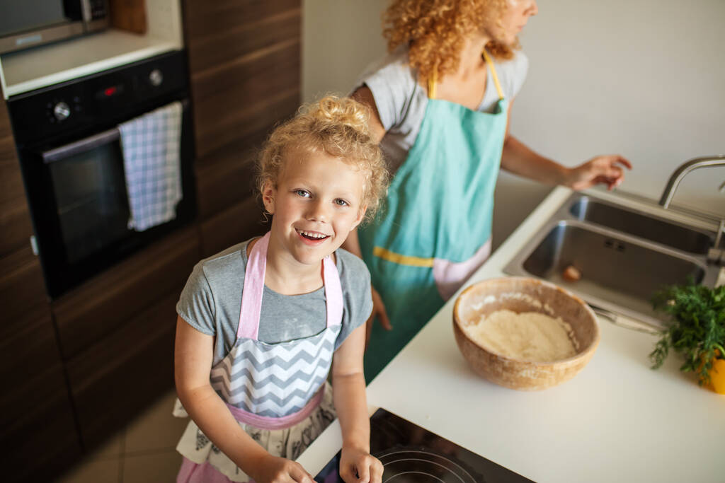 Attraktive junge Frau und ihre kleine süße Tochter kochen in der Küche. - Foto, Bild