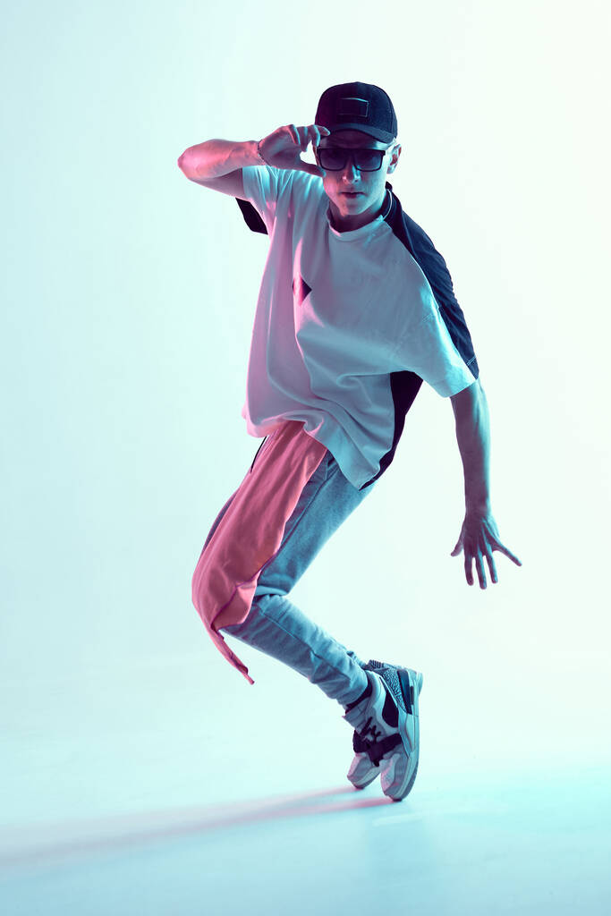 Menő fiatal srác kortárs táncot táncol a stúdióban neon fényben. Szünet tánc órák. Tánciskola plakát - Fotó, kép