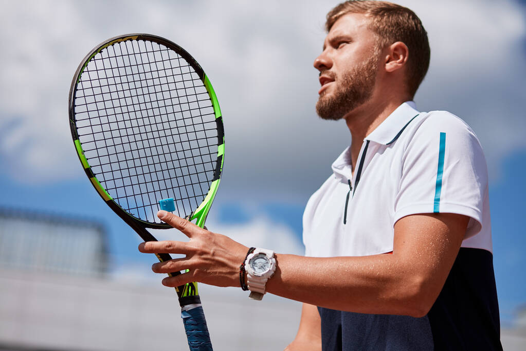 Mladý muž ve sportovním oblečení hraje tenis na dvorku. - Fotografie, Obrázek