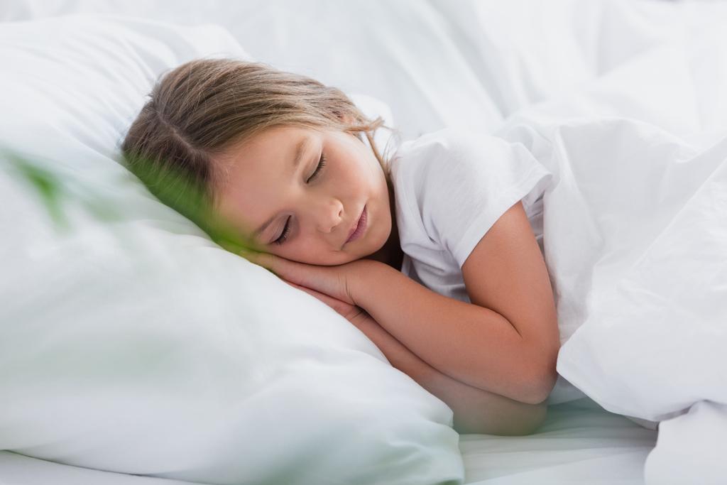 valikoiva painopiste tyttö nukkuu kun makaa valkoinen vuodevaatteet - Valokuva, kuva