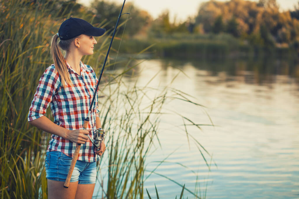 Linda mujer está pescando con caña en el lago - Foto, imagen