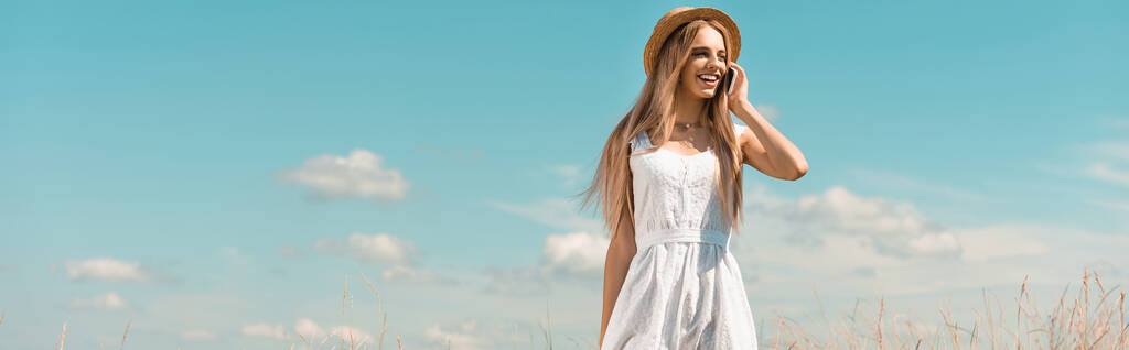 sivusto otsikko blondi nainen olki hattu ja valkoinen mekko puhuu älypuhelimeen vastaan sininen taivas - Valokuva, kuva