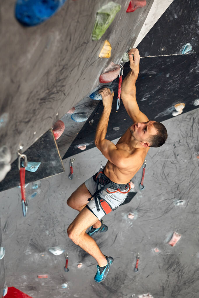 Male professional climber at indoor workout at bouldering centre. - Photo, Image