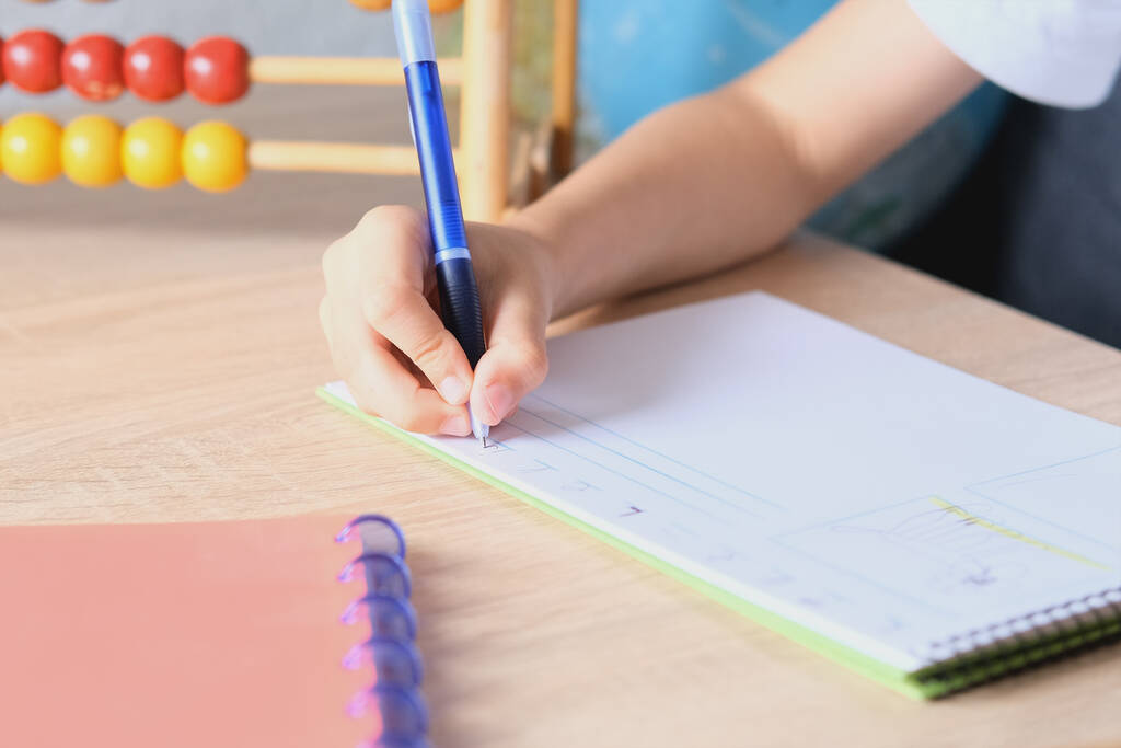 enfant écrit et dessine dans un carnet sur une table en bois, le concept du début de l'année scolaire, devoirs, leçons, retour à l'école - Photo, image