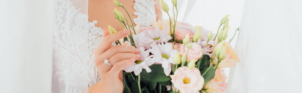 Panorama-Ernte der Braut berührt Blumenstrauß in der Nähe von Vorhängen  - Foto, Bild