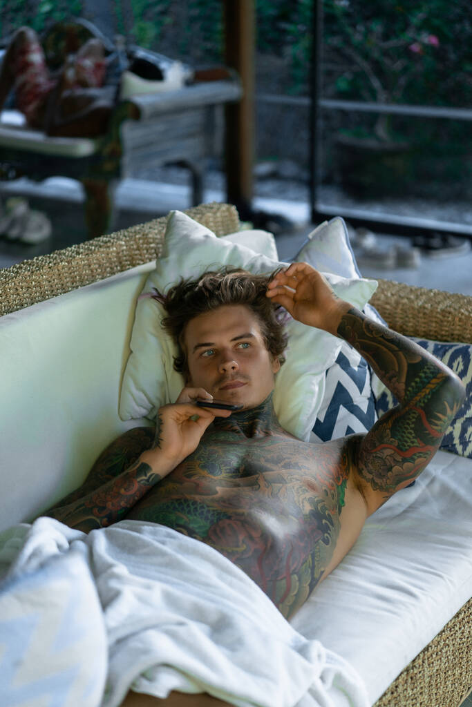 красивий молодий чоловік в татуюваннях відпочиває у вітальні
 - Фото, зображення