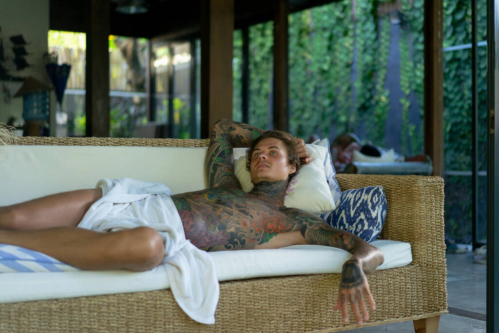 bello giovane uomo in tatuaggi sta riposando in soggiorno - Foto, immagini
