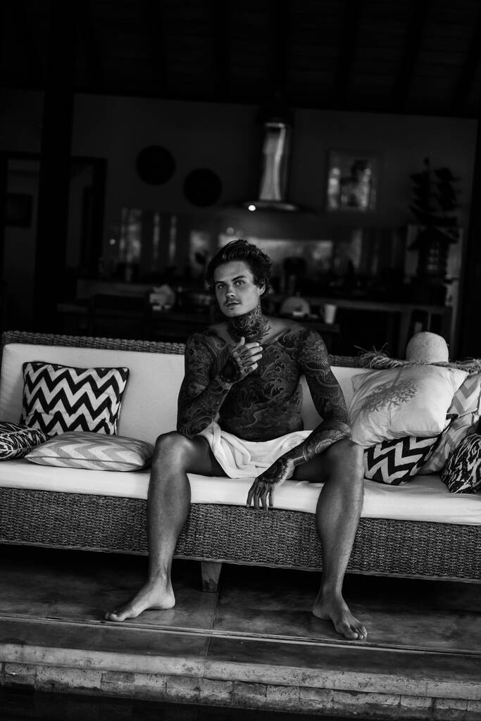 jóképű, tetovált fiatalember pihen a nappaliban. - Fotó, kép