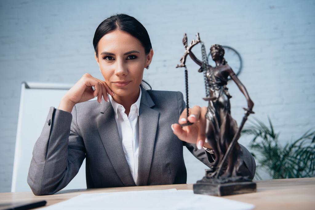 selective focus of lawyer in formal wear touching statuette of justice in office - Photo, Image
