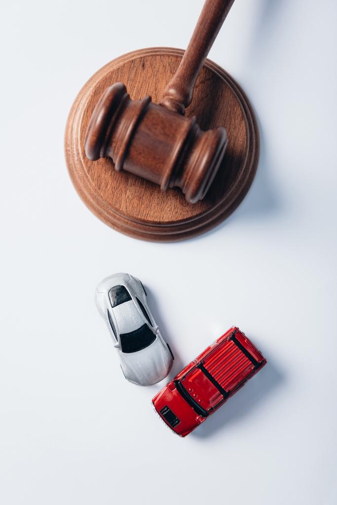 vista superior de los coches de juguete cerca de martillo de madera en blanco, concepto de seguro  - Foto, imagen