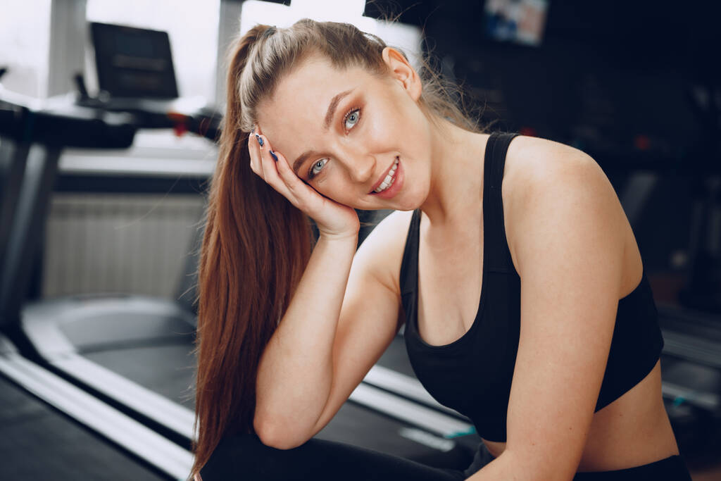 Esmer, genç bir kadın spor salonunda yorgun oturuyor. - Fotoğraf, Görsel