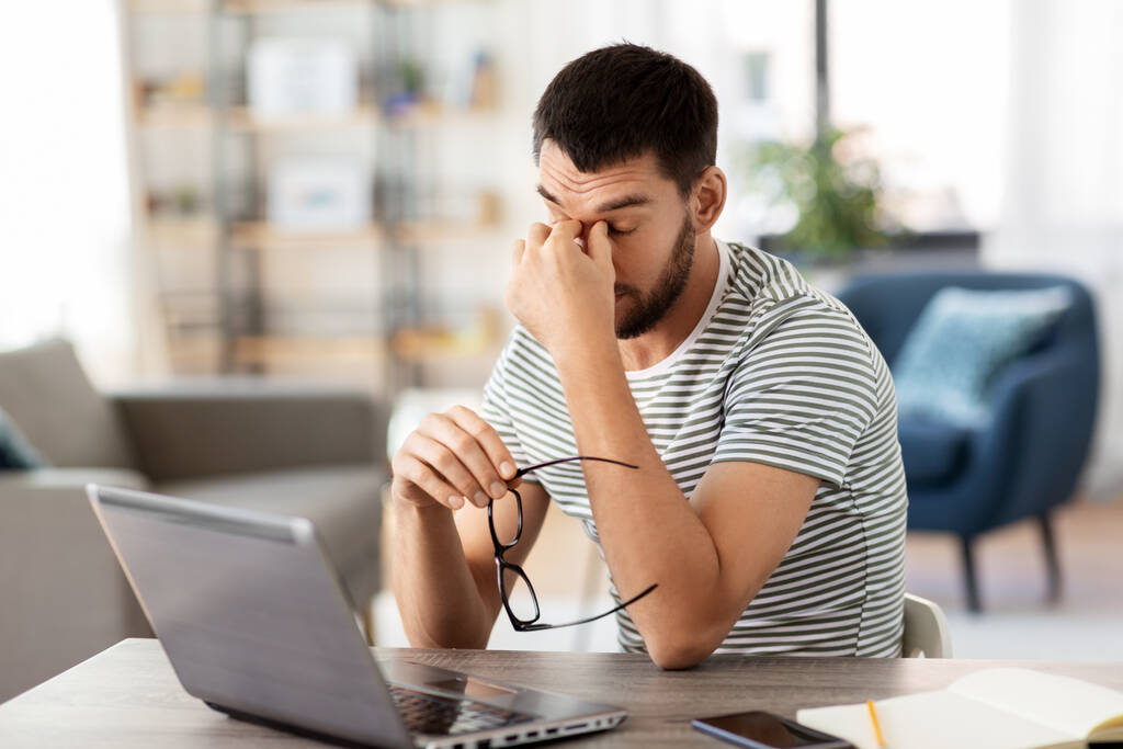 κουρασμένος άνθρωπος με φορητό υπολογιστή που εργάζονται στο γραφείο στο σπίτι - Φωτογραφία, εικόνα