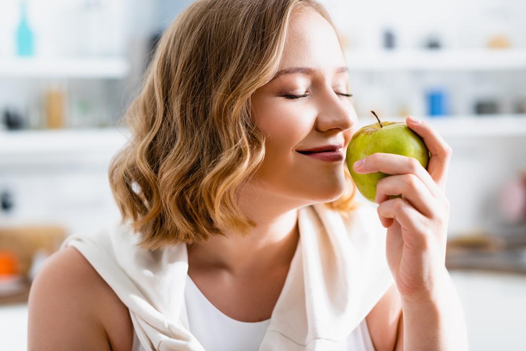 молодая женщина с закрытыми глазами пахнет зеленым яблоком - Фото, изображение