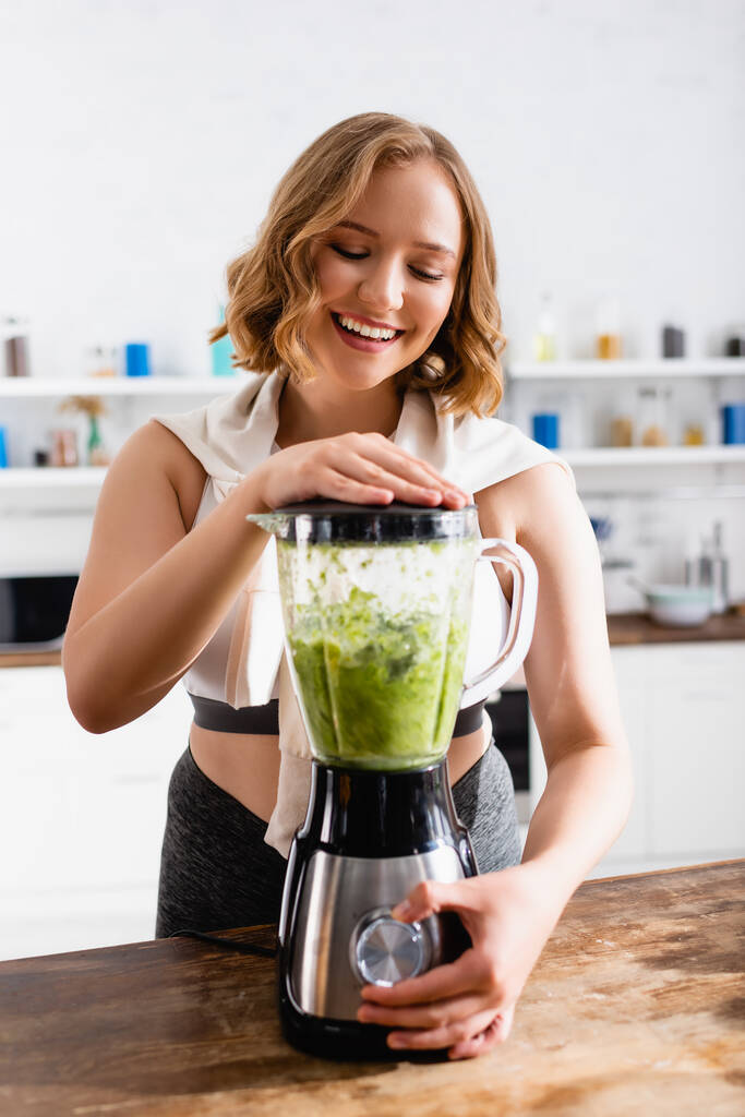 junge Frau mixt grünen Smoothie im Mixer  - Foto, Bild