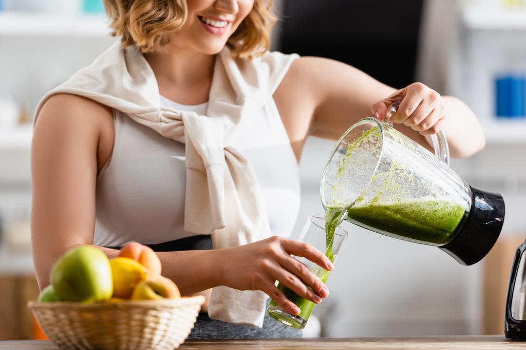 Teilbild einer jungen Frau, die grünen Smoothie in Glas gießt  - Foto, Bild