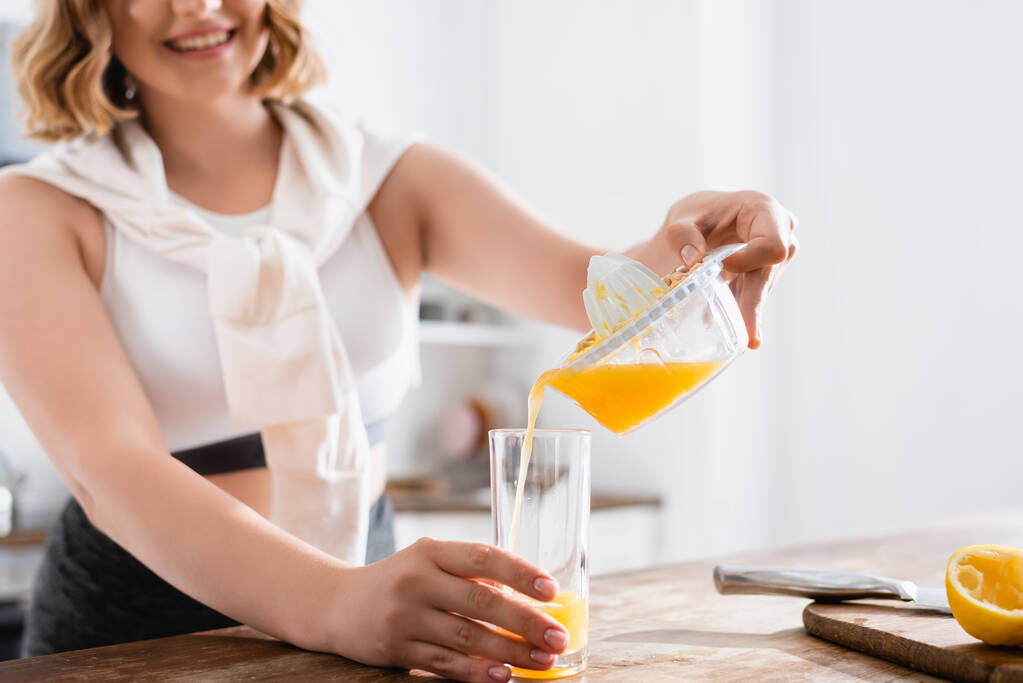 新鮮なオレンジジュースをグラスに注ぐ女性のクロップドビュー  - 写真・画像