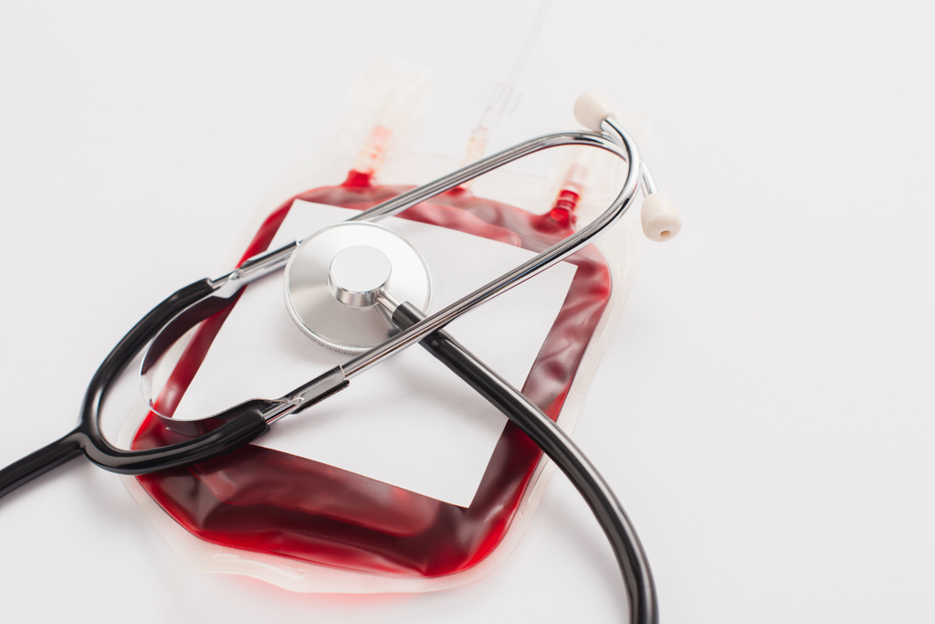 Blutspendepaket mit Blanko-Etikett und Stethoskop auf weiß - Foto, Bild
