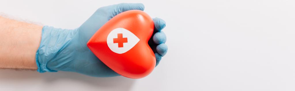 Beyaz üzerinde kırmızı kalp olan lateks eldivenli erkek eli, kan bağışı konsepti. - Fotoğraf, Görsel