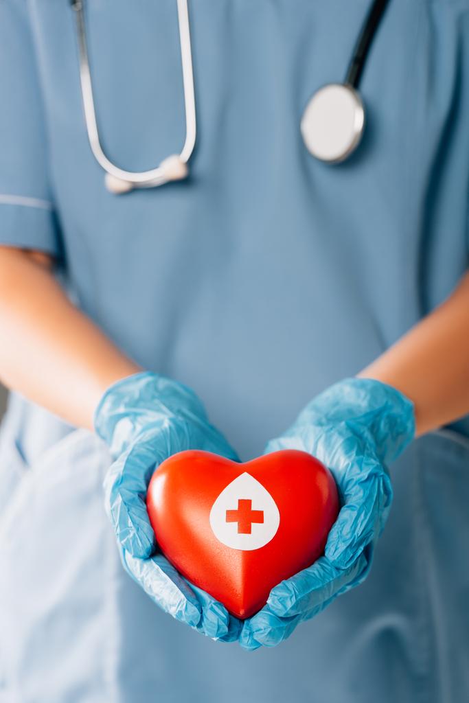 oříznutý pohled na lékaře se stereoskopem s červeným srdcem, koncept darování krve - Fotografie, Obrázek