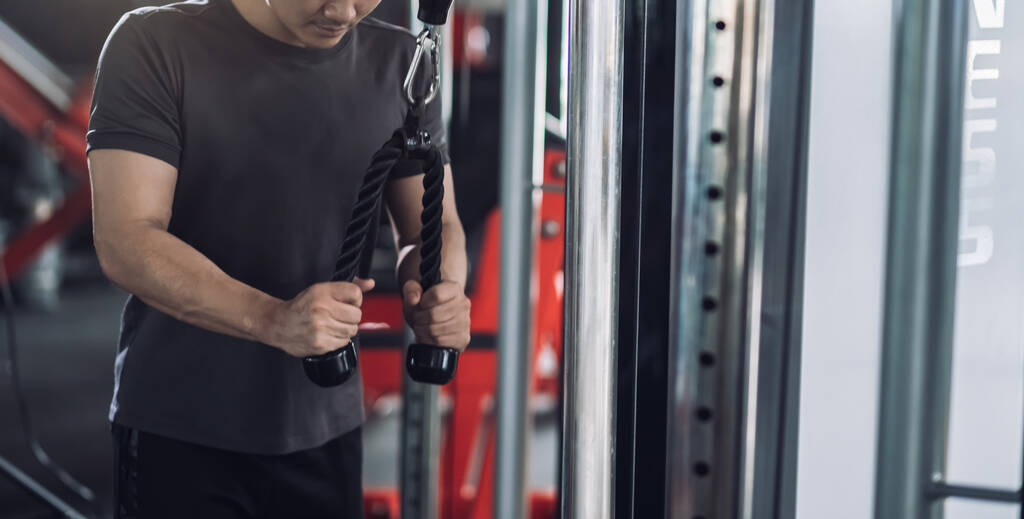 Αθλητής κάνει ασκήσεις με καλώδιο tricep μηχάνημα στο γυμναστήριο, Fit άσκηση εστίαση bicep και των μυών του ώμου σε ενεργό υγιή τρόπο ζωής bodybuilding. - Φωτογραφία, εικόνα