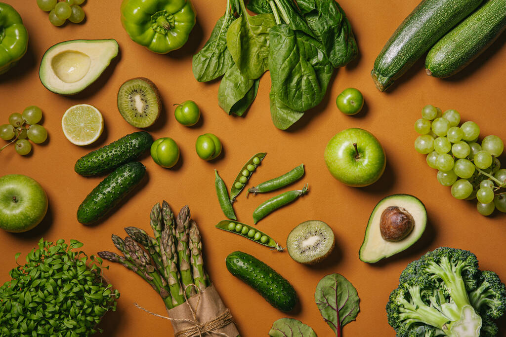 Groene groenten en fruit, groenten en peulvruchten op oranje achtergrond. Gezond eten en schoon eten concept. Vlakke lay, bovenaanzicht. - Foto, afbeelding