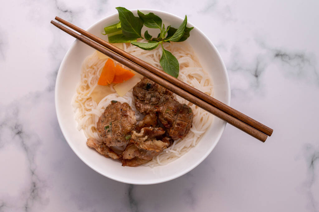 Высокий угол съемки азиатского блюда с лапшой и мясом, с палочками на мраморной поверхности - Фото, изображение