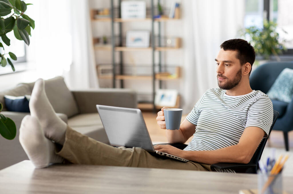 Mann mit Laptop trinkt zu Hause Kaffee - Foto, Bild
