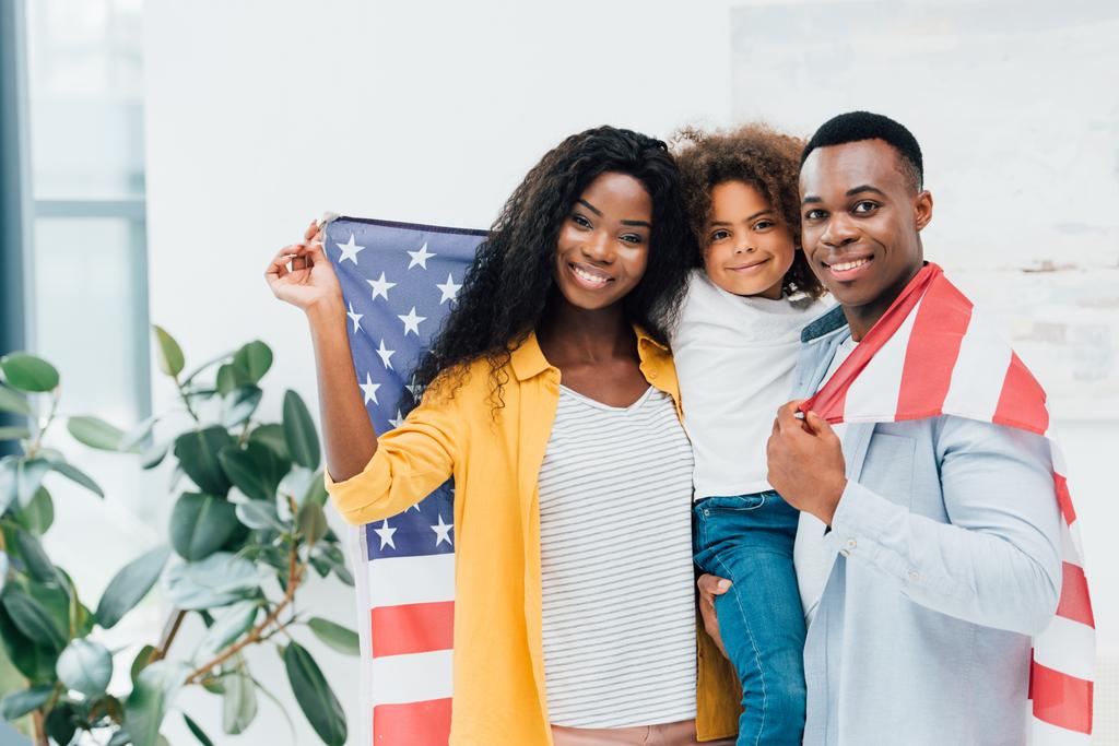 Αφρο-αμερικανική οικογένεια που κρατά σημαία της Αμερικής και κοιτάζει την κάμερα  - Φωτογραφία, εικόνα