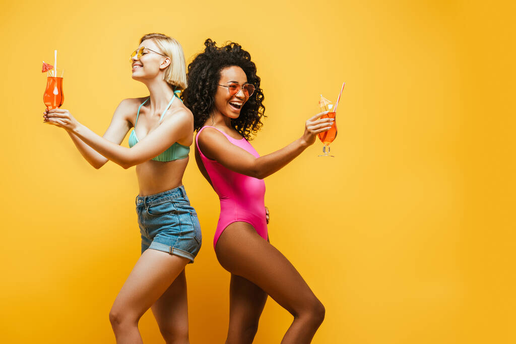 fiatal multikulturális nők nyári ruhában, háttal állva, koktélszemüveggel a sárgán - Fotó, kép