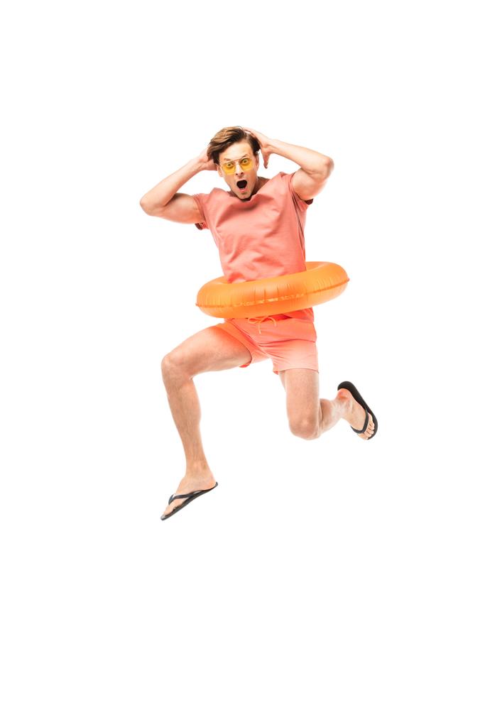 Hombre sorprendido en gafas de sol y anillo de natación saltando aislado en blanco - Foto, Imagen